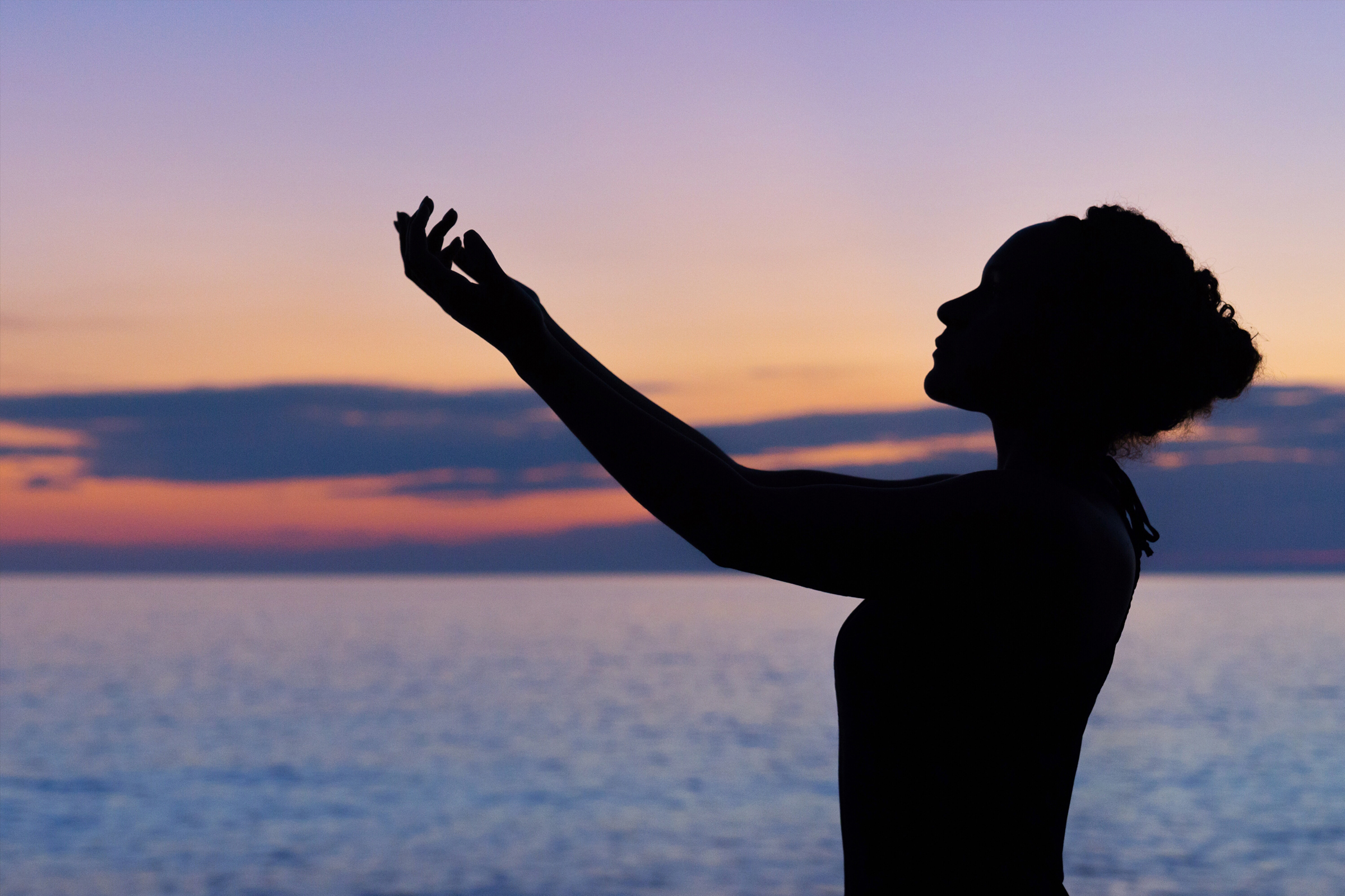 A person standing on the beach with their hands up.