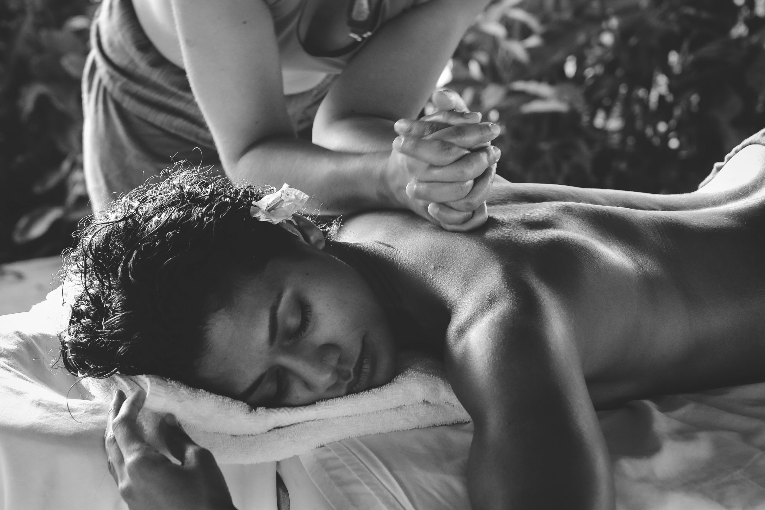 A woman with flower in ear getting back massage