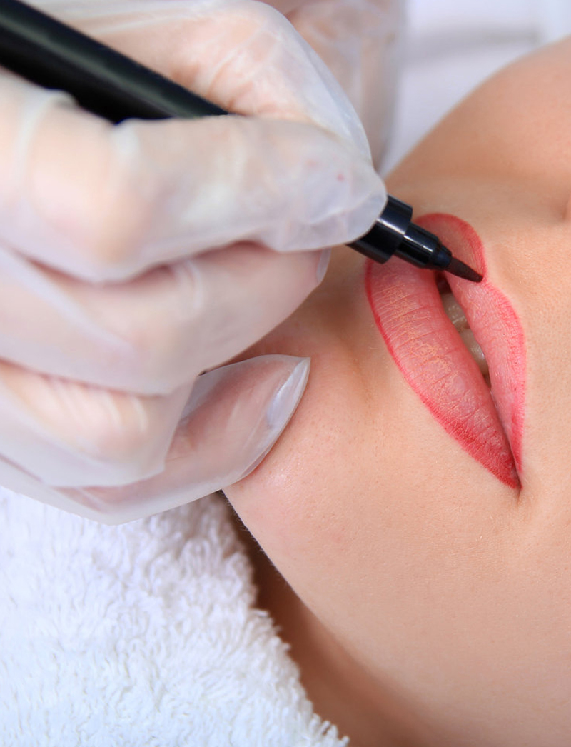 Beautician drawing lip liner to the client lips