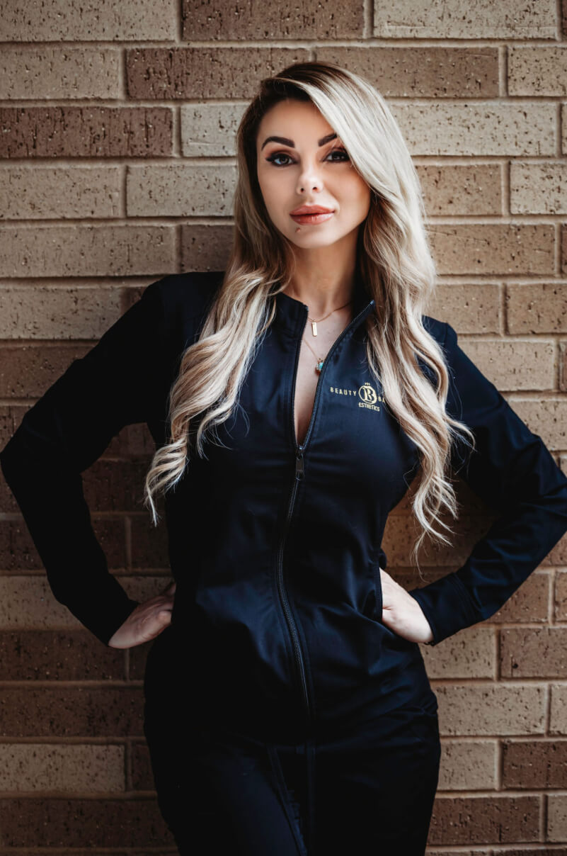 A woman standing in front of a brick wall.