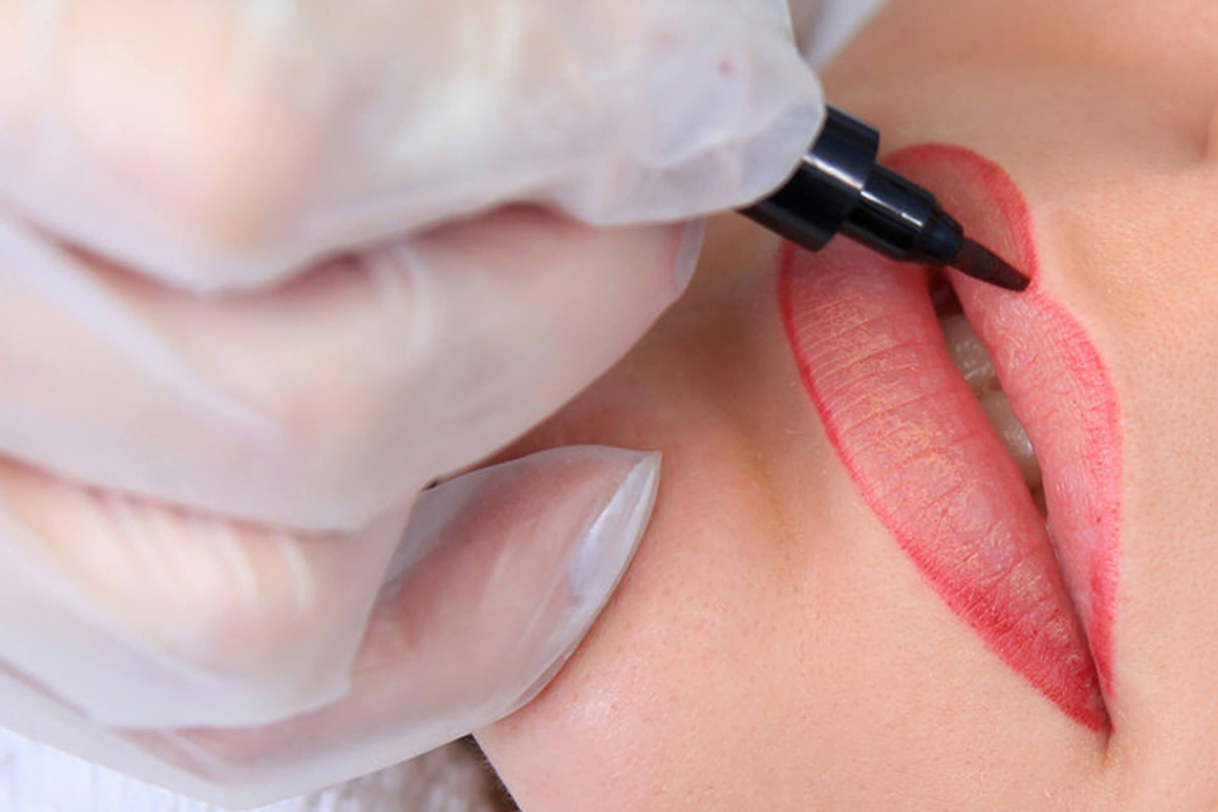 A person with gloves on is getting their lips painted