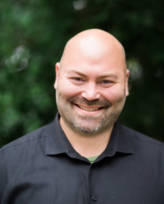 A man with bald head smiling for the camera.